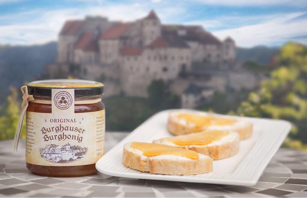 Honigglas und Honigbrot und im Hintergrund die Burg Burghausen, &copy; Alztalhonig